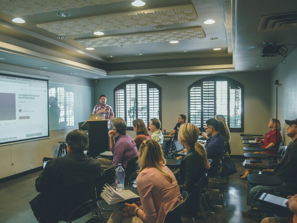A facilitator leading a training session for a seated group of students.